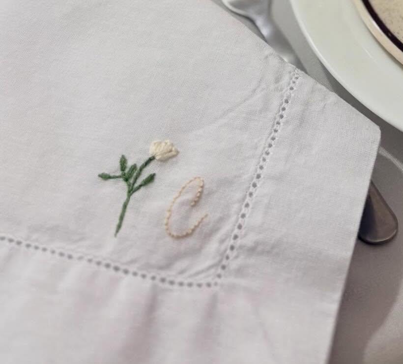 Detalhe de guardanapo de mesa com flor e inicial bordadas